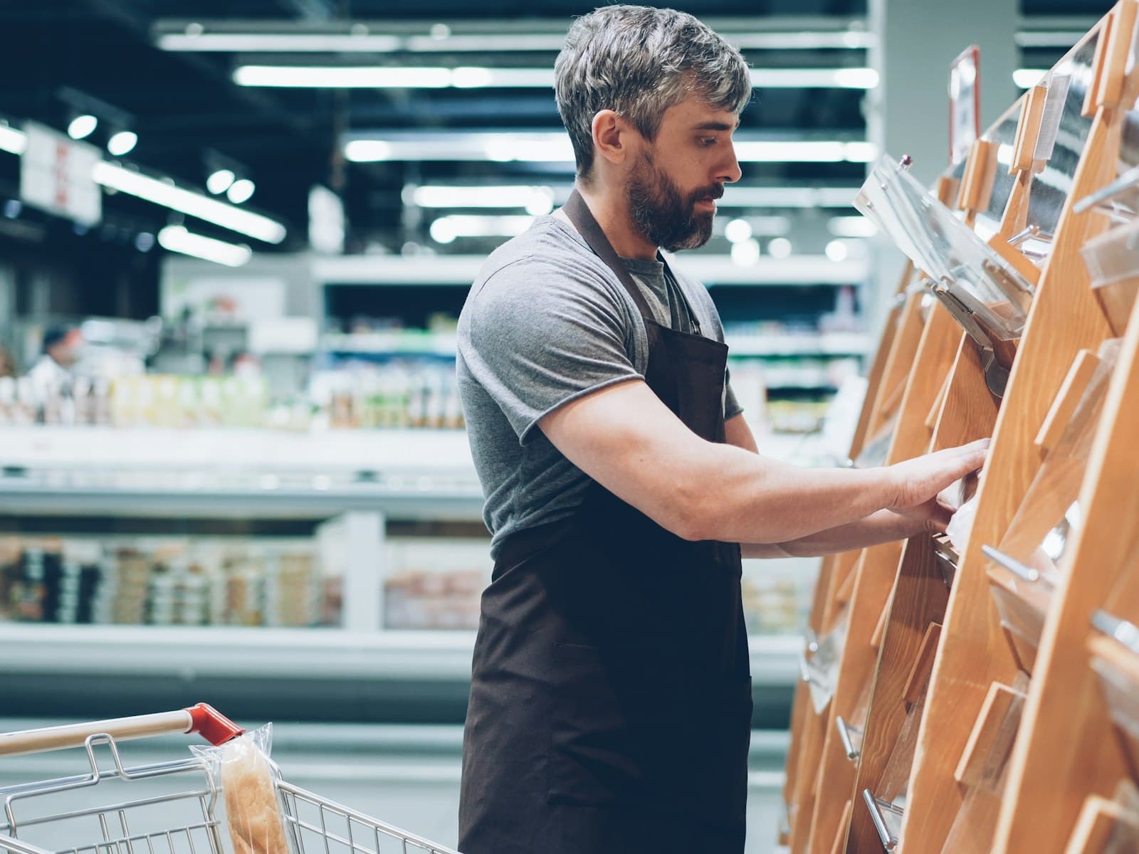 Shop worker in an apron restocking a store display